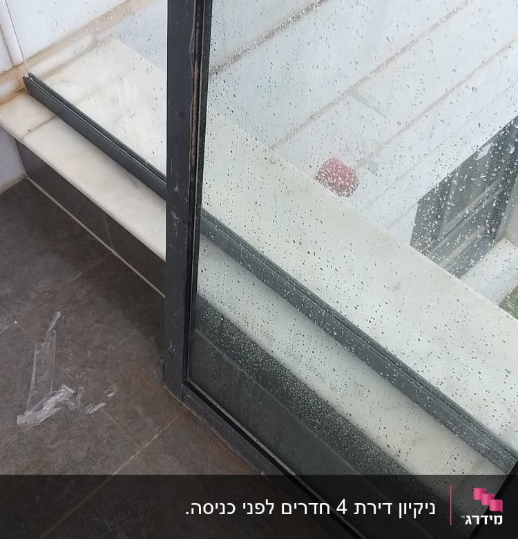 חלון מלוכלך עם טיפות מים ופסולת פלסטיק על הרצפה